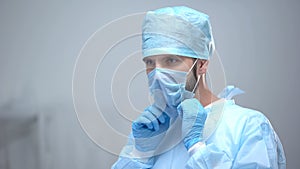 Surgeon wearing medical face mask, preparing for operation, sterility condition