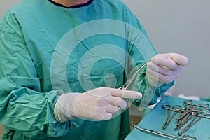 Surgeon, wearing medical protective gloves skillfully maneuvered sterile forceps needle holder