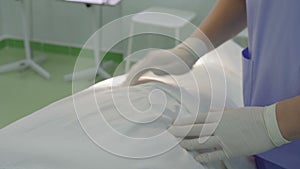 Surgeon in white protective rubber gloves, palpates the patient on the table in the operating room in the hospital