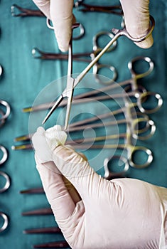 Surgeon working in operating room, hands with gloves holding scissors with torunda, conceptual image
