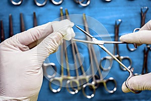 Surgeon working in operating room, hands with gloves holding scissors with torunda, conceptual image