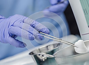 Surgeon working in operating room, hands with gloves holding scissors with torunda, conceptual image