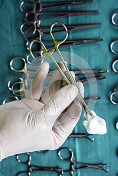 Surgeon working in operating room, hands with gloves holding scissors with torunda, conceptual image