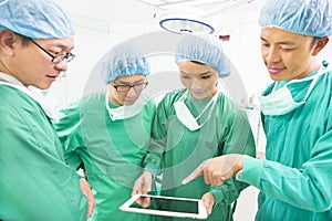 Surgeons discussing with tablet in operating theater