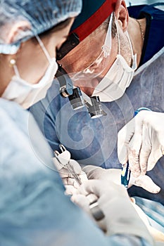 Surgeons men and women in one team during an operation over the operating table, doctors in modern equipment perform an