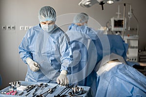 Surgeons prepare sterile medical instruments for surgery