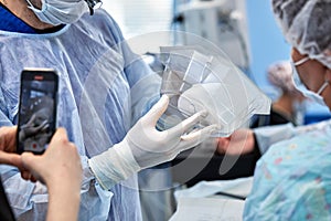 Surgeons during surgery with breast implants in their hands, installation of breast implants, surgery. Plastic surgery