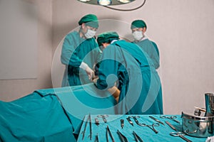 Surgeons team performing surgery a seriously injured patient and picking up medical equipment in operating room at hospital