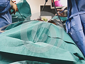 Surgeons using surgical instruments for keyhole surgery, watching the monitor which displays images from inside the patient`s abdo