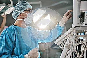 Surgery, machine and doctor with monitor in hospital for healthcare, theatre operation or analysis. Medical, man and