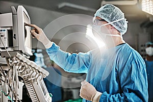 Surgery, machine and doctor with monitor in theatre for healthcare, cardiovascular operation or analysis. Medical