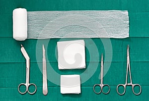 surgery tools ,scissors ,roll gauze,bandage,pad,cramp,blade,knife on green surgical dress background ,bird eye view