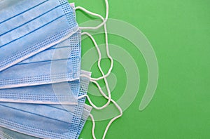 Surgical disposable face masks on green background with copy space. Top view.