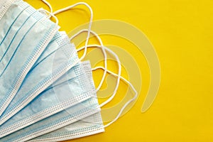 Surgical disposable face masks on yellow background with copy space.