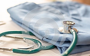 Surgical doctor gown on working table in medical clinic with stethoscope for heart and cardiological diagnostic exam and surgeon`s photo
