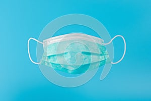 Surgical face mask on blue backdrop. Minimal medical concept photo
