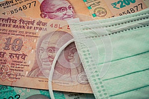 Surgical face mask on Indian rupee bill banknote background. Global novel coronavirus Covid-19 outbreak effect to world economy