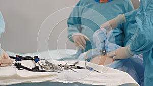 Surgical hospital specialist team in scrubs in operating theatre performing laparoscopic surgery using video monitor