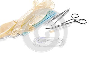 Surgical instruments forceps for closing a wound, curved tweezers, thread with needle, medical mask and rubber gloves on white bac