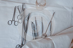 Surgical instruments made of steel including scalpels, forceps and tweezers, located on a white table. Medical equipment. Close-up