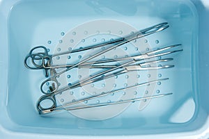Surgical instruments are rinsed in a tray with water.