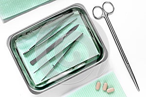 Surgical instruments and tools including scalpels, forceps and tweezers on white table top view