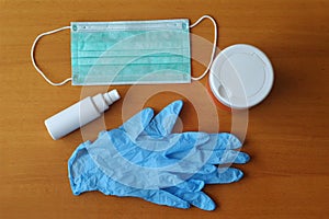 Surgical mask, latex gloves, hand sanitizer and antiseptic wet wipes on wooden background. Coronavirus protection