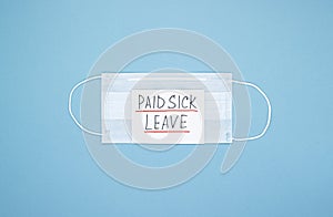 Surgical masks rubber ear straps with the words paid sick leave on a blue background