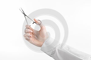 Surgical and Medical theme: doctor's hand in a white lab coat holding a surgical clamp scissors isolated on a white background