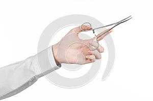 Surgical and Medical theme: doctor's hand in a white lab coat holding a surgical clamp scissors isolated on a white background