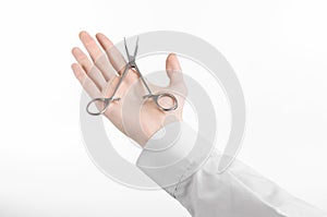 Surgical and Medical theme: doctor's hand in a white lab coat holding a surgical clamp scissors isolated on a white background