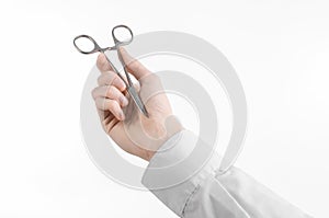 Surgical and Medical theme: doctor's hand in a white lab coat holding a surgical clamp scissors isolated on a white background