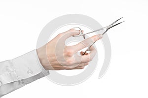 Surgical and Medical theme: doctor's hand in a white lab coat holding a surgical clamp scissors isolated on a white background