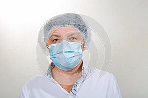 Surgical Nurse in cap and mask in medical clinic. Close-up portrait. Health care, surgery. Working in the face of the coronavirus