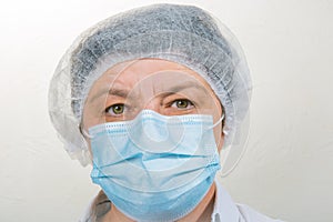 Surgical Nurse in cap and mask in medical clinic. Close-up portrait. Health care, surgery. Working in the face of the coronavirus