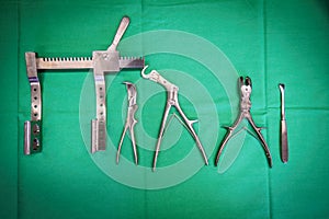 surgical rib instruments lie on a green surgical cloth