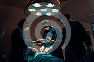 Surgical team performing surgery to patient in sterile operating room.