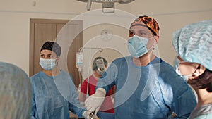 Surgical Team Working In Operating Theatre. During the operation in the operating room, a nurse or assistant fixes the