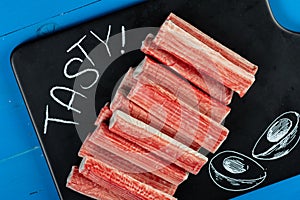 Surimi Sticks On The Black Tray With Tasty Text Sign