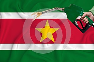 SURINAME flag Close-up shot on waving background texture with Fuel pump nozzle in hand. The concept of design solutions. 3d