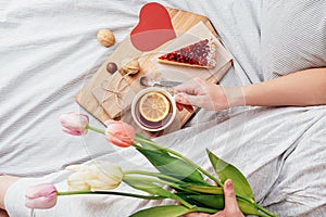 Surprise in bed. Breakfast, flowers and a gift for a girl on Valentine`s Day. congratulations for February 14