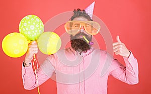 Surprise birthday party with balloons decoration. Bearded man in pink shirt showing thumb up. Hipster with huge glasses