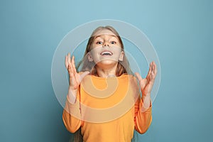 The surprise, happiness, joy, victory, success and luck. Teen girl on a blue background. Facial expressions and people