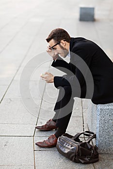 Surprise on face of young business man sitting on street. Shocking news