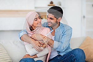 Surprise and future parents. Happy young muslim spouses holding positive pregnancy test and smiling at each other