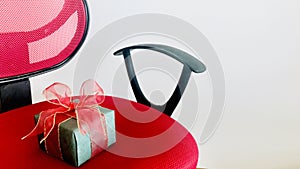 A surprise green gift box on red wheels chair over white background.