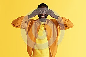 Surprise. Happy man closing eyes with hands on yellow background