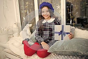Surprise for her. Kid at home relaxing on cozy window sill. Magic moment. Happy winter holidays. Small girl opening gift