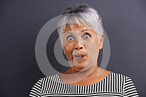 Surprise, portrait and senior woman in studio with crazy, silly or crazy facial expression for comedy. Shock, comic and
