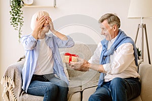 Surprise. Senior man giving present to wife